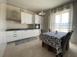 a kitchen with a table with chairs and white cabinets at Sottovento B&B in Trani