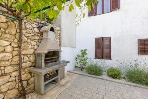 a stone oven sitting next to a stone wall at Home Away From Home with a heated pool in Punat