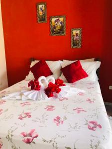 Pousada Casa Do Mar في باراتي: سرير بجدران حمراء وورود حمراء عليه