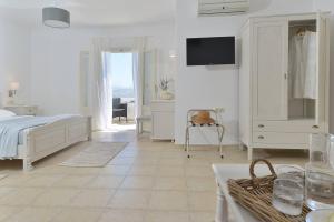 a white bedroom with a bed and a television in it at Hotel Mediterranean in Stelida