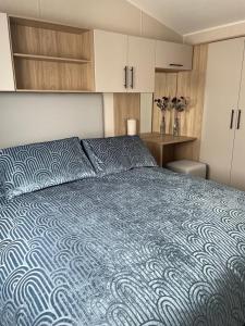 a bedroom with a large bed with a blue comforter at Dune View Caravan in Lossiemouth