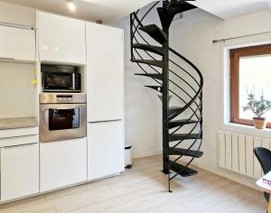 a spiral staircase in a kitchen with white cabinets at Studio, chambres, appartement, gite in Vendegies-sur-Écaillon