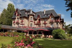 a large building with tables and chairs in front of it at Le Castel Marie Louise in La Baule