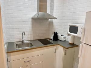 a small kitchen with a sink and a microwave at Apartamentos Caspe in Caspe