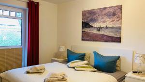 a bedroom with a bed with blue pillows and a painting at FEWO II Villa Nicole Hafenstraße 37 in Zingst