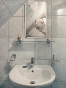 uma casa de banho com um lavatório branco e um espelho. em Rita Vendégház em Ciumani