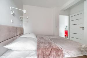 - une chambre avec un grand lit aux murs blancs dans l'établissement Apartament 2000 Stare Miasto Apartamenty No 1, à Szczecin