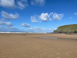 a sandy beach with a blue sky and clouds at The Potting Shed in St Austell