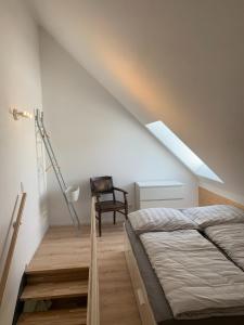 een slaapkamer met een bed, een ladder en een stoel bij Blackforest Homestay in Herrischried