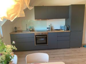 a kitchen with gray cabinets and a white chair at Blackforest Homestay in Herrischried