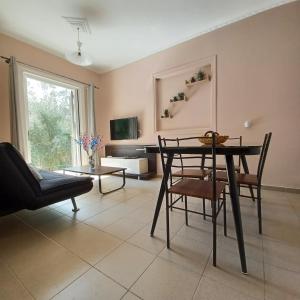 sala de estar con mesa, sillas y TV en Μπουκαμβίλια - Bougainvillea, en Sivota