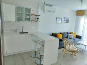 プラヤ・オンダにあるApartamento Las Playasの白いキャビネットと青いソファ付きのキッチンが備わります。
