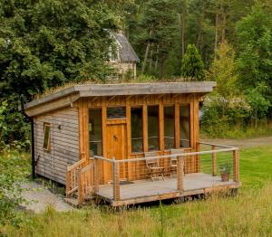 a wooden cabin with a porch in a field at Caledonian Glamping in Cannich