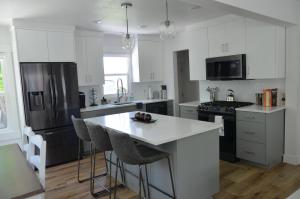 una cocina con armarios blancos y una isla de cocina con taburetes en Lincoln Street House en Salt Lake City