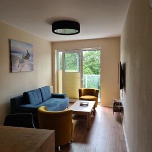 a living room with a blue couch and chairs at Apartament Centrum in Koszalin