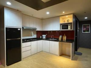 een keuken met witte kasten en zwarte apparaten bij 2BR Lovely Condo Amazing City View Lexington Residence in Jakarta