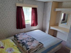 a small bedroom with a bed and a window at Mobilūs nameliai 'Zelma' in Palanga