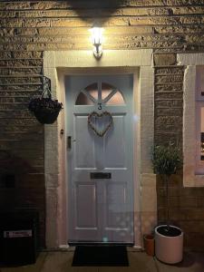 uma porta branca com uma coroa de flores no coração em Cute and cosy 2 bed cottage em Honley
