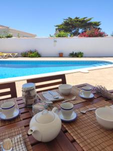 a table with a tea set next to a pool at Villa Coral in Cala en Porter