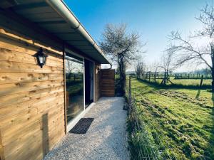 a wooden building with a walkway next to a field at Chambre avec spa privé in Candor