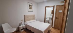 a white bedroom with a bed and a chair at Hotel Europa in Cambados