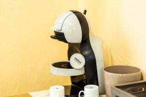una macchinetta del caffè in bianco e nero su un tavolo con tazze di La Casa del Postino a Farigliano