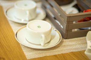 due tazze bianche e piattini su un tavolo di La Casa del Postino a Farigliano
