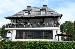 a house with a balcony with flowers on it at Enjoyit Rooms in Velden am Wörthersee