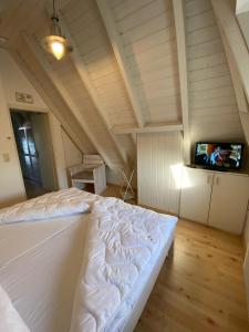 a bedroom with a white bed and a tv at Dat Onnens Hus - Nordisch mit Herz in Dorum-Neufeld