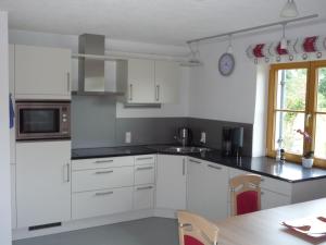 a white kitchen with white cabinets and a table at Ferienwohnung Aletsee in Pfronten
