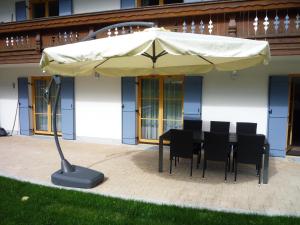 a table and chairs under an umbrella in front of a building at Ferienwohnung Aletsee in Pfronten
