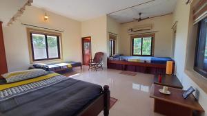 a bedroom with two beds and a room with two chairs at Shivalaya Boutique Stay in Tiruvannāmalai
