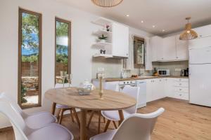 a kitchen with a wooden table and white chairs at Villa Ionio Deste by Villa Plus in Vasilikos