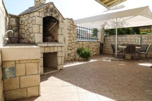 an outdoor patio with a stone fireplace and an umbrella at Adria Apartment in Hvar