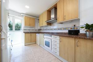 a kitchen with wooden cabinets and a large window at Hauzify I Apartament Cala Pepo 1 in L'Ametlla de Mar