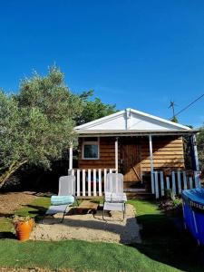 a small house with two chairs and a porch at Un chalet dans les oliviers 3 nuits mini in Nîmes