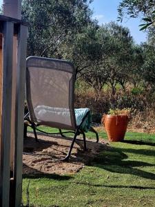 a chair sitting in the grass in a yard at Un chalet dans les oliviers 3 nuits mini in Nîmes