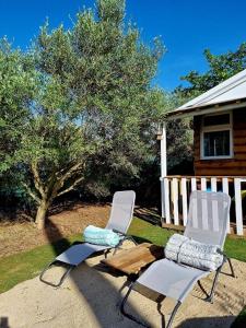 two white chairs sitting in front of a house at Un chalet dans les oliviers 3 nuits mini in Nîmes