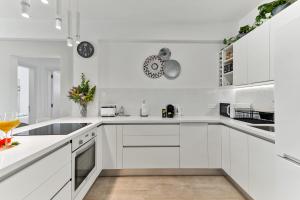 a white kitchen with white cabinets and appliances at Dreamy 2 bed apartment by the sea in Paphos