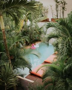 a swimming pool in a garden with palm trees at The Strabon Tulum in Tulum