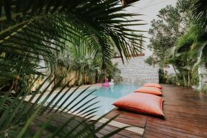 a swimming pool with orange pillows on a wooden deck at The Strabon Tulum in Tulum