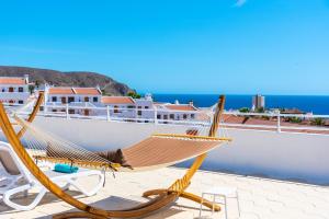 a hammock on a roof with a view of the ocean at Club Tenerife Apartments in Los Cristianos