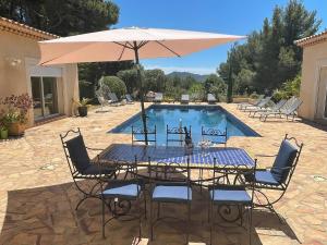 a table with an umbrella next to a pool at Maison d'Hotes Le Boulou in Saint-Cyr-sur-Mer