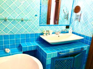 a blue tiled bathroom with a sink and a toilet at Villa Franci in Santa Teresa Gallura