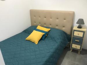 a bed with a blue comforter and a yellow pillow at Superbe studio entièrement refait a neuf in Figeac