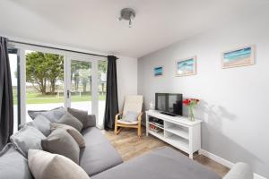 a living room with a couch and a tv at Wheal Prosper- Beautifully Fitted Wooden Lodge Helston Cornwall in Helston
