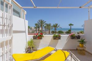a balcony with a yellow bench and a view of the ocean at Right on the beach in Benalmádena