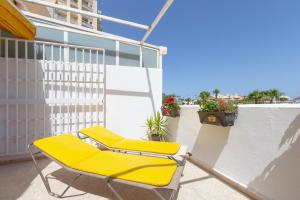 a pair of yellow lounge chairs on a balcony at Right on the beach in Benalmádena