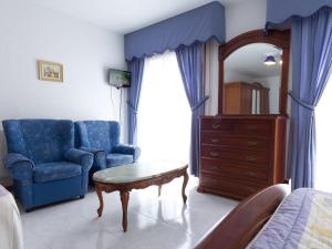 a bedroom with a couch and a table and a chair at Hotel Restaurante Xaneiro in Melide