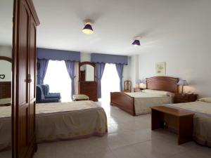 a hotel room with two beds and a chair at Hotel Restaurante Xaneiro in Melide